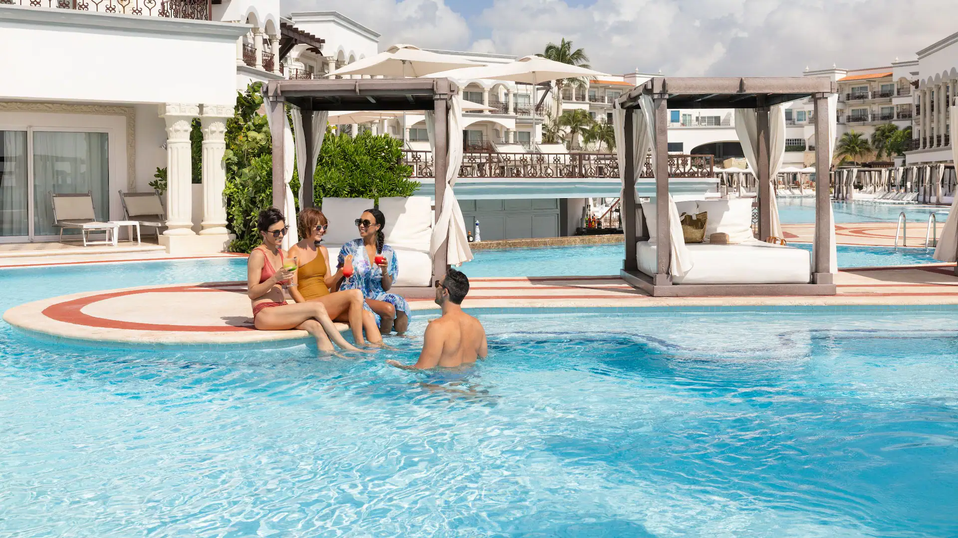 Friends enjoying cocktails in the main pool area at Hyatt Vivid Playa del Carmen with luxury cabanas nearby.