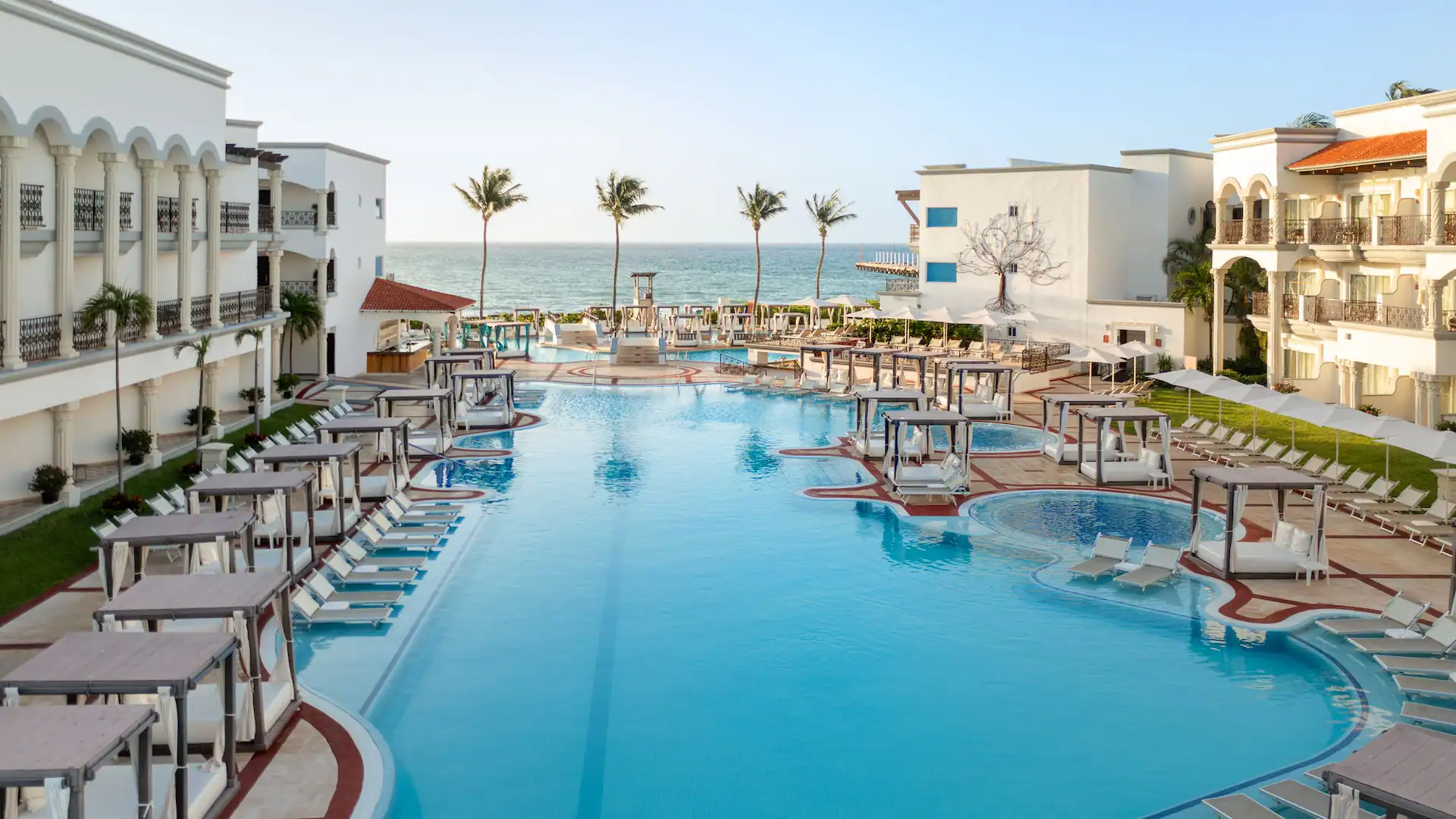 Expansive oceanfront pool with luxury cabanas at Hyatt Vivid Playa del Carmen, an adults-only all-inclusive resort in Riviera Maya.
